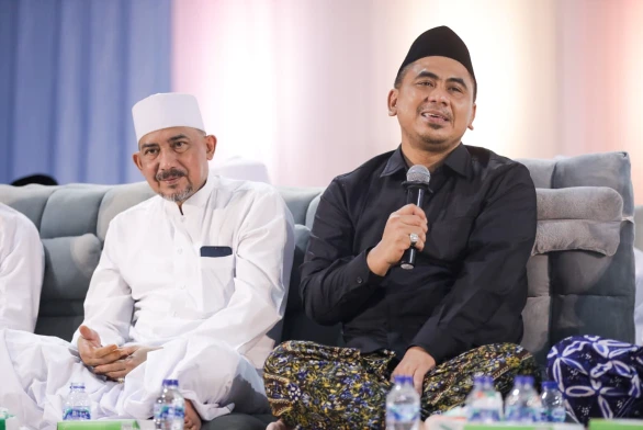 Gus Yasin Maimoen, berpakaian kemeja hitam dan peci hitam, sedang berbicara menggunakan mikrofon di hadapan jemaah pada acara Haul ke-7 KH Maimoen Zubair, ditemani seorang tokoh lain yang berpakaian jubah putih.