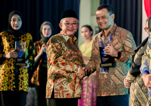 Mendikdasmen Abdul Mu'ti (kiri) berjabat tangan menyerahkan trofi penghargaan kepada Gubernur Ahmad Luthfi (kanan) atas keberhasilan program sekolah gratis Jateng pada peringatan Hari Pendidikan.