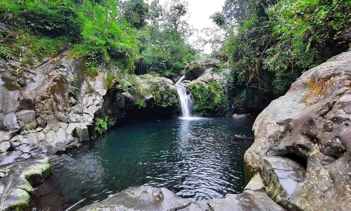 batu vulkanik serta pepohonan rimbun di Telaga Sunyi Baturaden, sebagai hidden gem wisata alam Jawa Tengah.