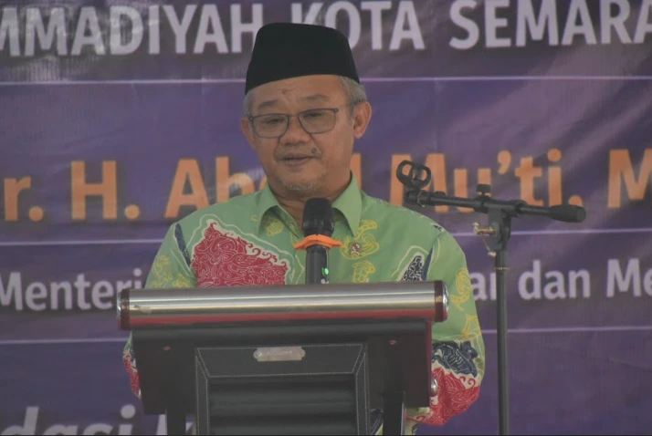 Foto medium H. Abdul Mu'ti, dengan peci dan batik hijau, berbicara di podium dengan mikrofon. Latar belakang spanduk Muhammadiyah Kota Semarang.