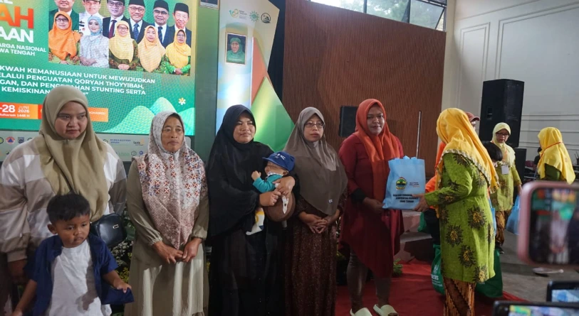 Penyerahan simbolis bantuan tas biru kepada perwakilan ibu dan anak oleh petugas berseragam hijau dalam acara Jambore Dakwah Kemanusiaan Aisyiyah Jateng di Wonderpark Tawangmangu untuk program cegah stunting.