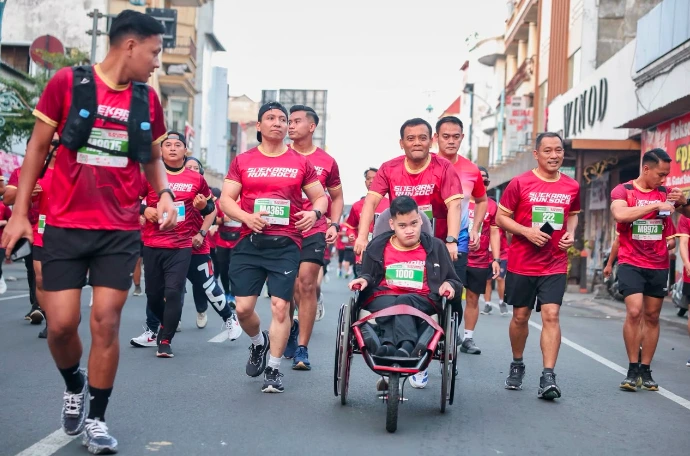 Gubernur Jawa Tengah Ahmad Luthfi berlari mendampingi sambil mendorong kursi roda balap putranya, membelah kerumunan ribuan peserta di lintasan aspal Soekarno Run 2026 Solo.