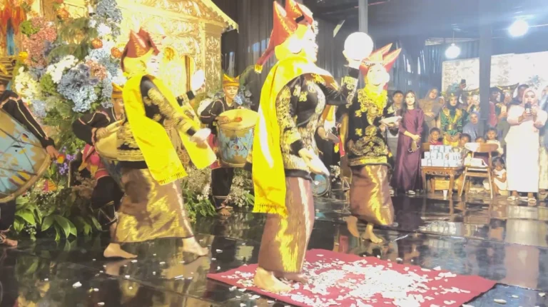 Penari berkostum adat Minangkabau sedang melakukan atraksi ekstrem Tari Piring injak beling di atas pecahan kaca tanpa alas kaki dalam resepsi pernikahan Minang