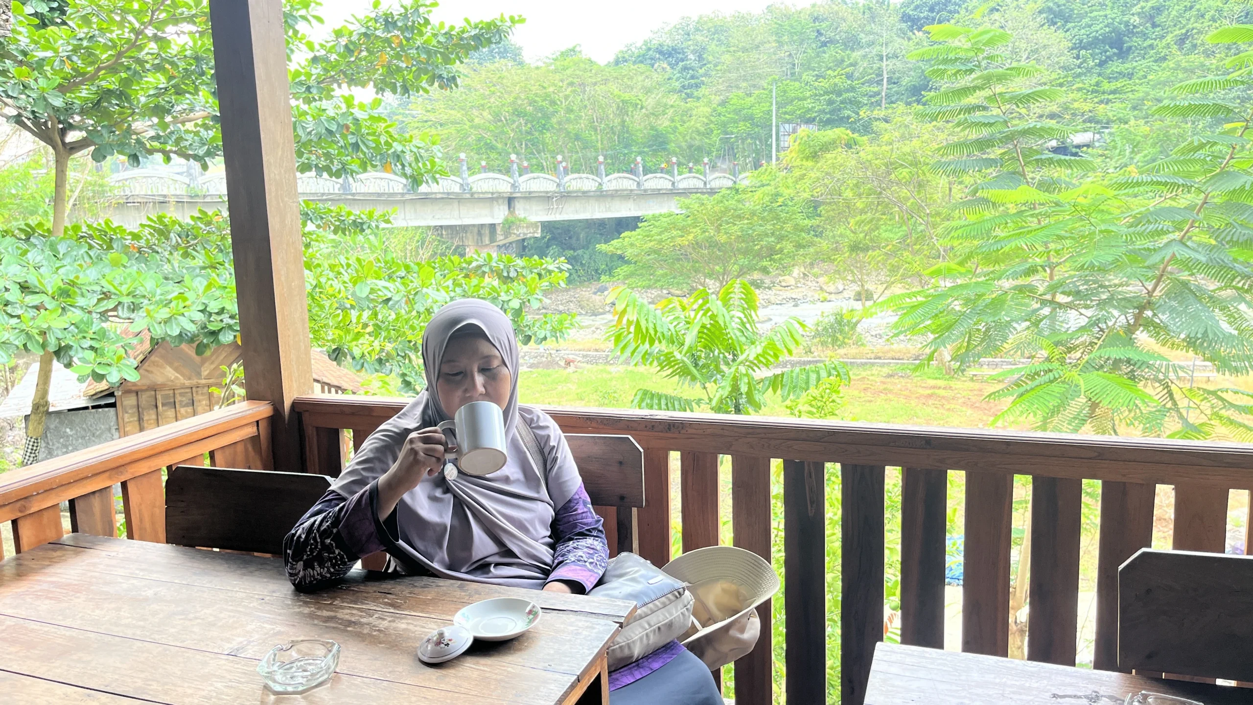 Dian Armanda menikmati minuman di teras Warung Omahe Mbah Kung, tempat healing Semarang tepi Sungai Kaligarang.