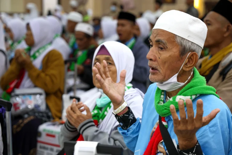 Seorang jemaah haji lansia pria mengangkat kedua tangan berdoa penuh haru saat tiba di Asrama Haji Donohudan, menandai dimulainya jadwal kepulangan haji 2026 kloter pertama.