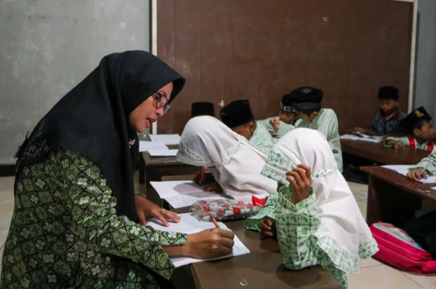 Guru ngaji perempuan di TPQ Jawa Tengah sedang membimbing santri belajar, ilustrasi penerima insentif guru agama madrasah.