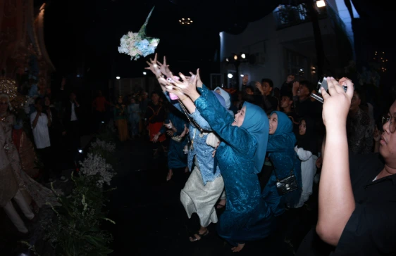 Sekelompok tamu perempuan berhijab biru toska dengan antusias berebut menangkap lemparan buket bunga pengantin pada acara resepsi pernikahan di Pesawaran Lampung.