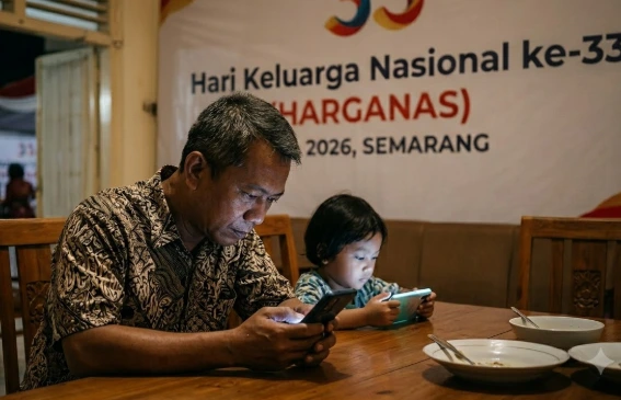 Potret ayah dan anak yang sibuk dengan gawai masing-masing di meja makan dengan latar spanduk Hari Keluarga Nasional ke-33 Semarang, mengilustrasikan krisis interaksi dan pentingnya peran ayah dalam keluarga untuk mencegah bahaya gadget.