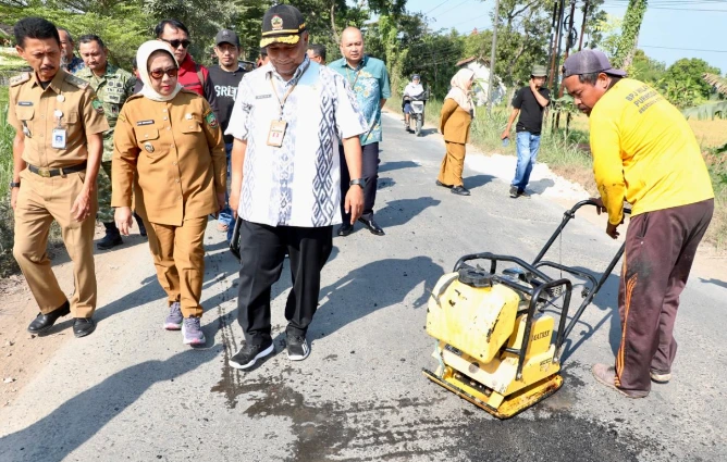 Pekerja menambal jalan rusak disaksikan pejabat daerah dalam tahap awal proyek perbaikan jalan Blora ruas Randublatung-Cepu.