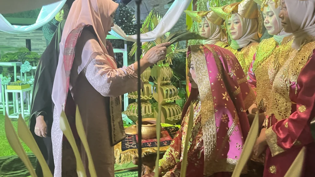 Sesepuh keluarga memercikkan air kembang kepada calon pengantin wanita Inthan dalam ritual mandi kembang rangkaian Malam Bainai di Pesawaran.