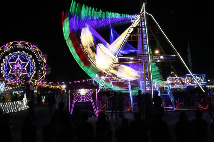 Suasana malam gemerlap pengunjung memadati area wahana permainan Kora-kora dan bianglala di Jateng Fair 2026 PRPP Semarang sebagai destinasi liburan sekolah murah di Jawa Tengah.