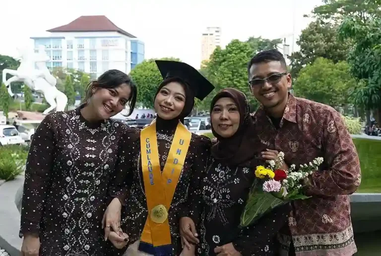 Marsya Wijayanti, anak penjual kue tenongan di Semarang, tersenyum bahagia mengenakan toga dan selempang Cumlaude saat perayaan wisuda UNDIP bersama ibu dan keluarganya, sukses wujudkan mimpi berkat beasiswa KIP.