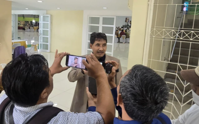 Dr. Ir. Mohammad Agung Ridlo, Ketua S2 PWK UNISSULA, dalam jas krem, berbicara saat direkam oleh jurnalis dengan smartphone di aula.