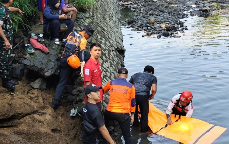 Tim SAR gabungan dari Basarnas, TNI, dan relawan mengevakuasi kantong jenazah oranye berisi korban bocah tenggelam di Banjarnegara dari aliran air berbatu.