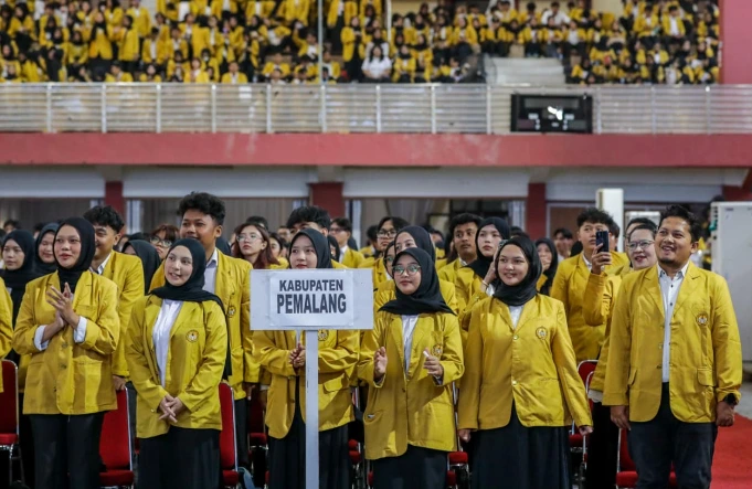Ribuan mahasiswa mengenakan jas almamater kuning mengikuti upacara pelepasan KKN Unsoed 2026 di Auditorium Graha Widyatama Purwokerto, tampak perwakilan kelompok memegang papan nama Kabupaten Pemalang.