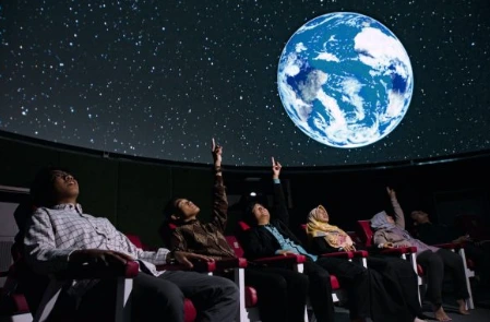 Pengunjung duduk di teater sambil menunjuk proyeksi bumi dan gugusan bintang di layar kubah Planetarium UIN Walisongo.