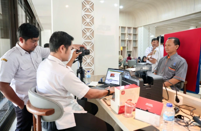 Petugas melayani warga mengambil foto KTP elektronik dalam kemudahan layanan urus KTP lintas daerah di Lounge Rumah Rakyat Jateng, Semarang.