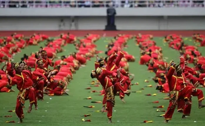 Ribuan pesilat berseragam merah melakukan atraksi jurus Pencak Budaya secara massal di lapangan hijau pada perhelatan Muktamar Tapak Suci 2026 di Semarang.