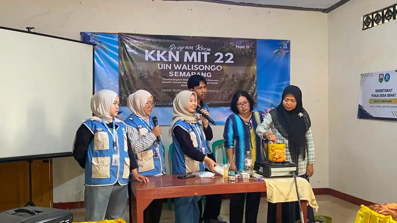 Mahasiswa KKN UIN Walisongo sedang memandu ibu-ibu PKK Desa Tlompakan mempraktikkan cara membuat lilin aromaterapi dari minyak jelantah di atas meja menggunakan kompor portabel.
