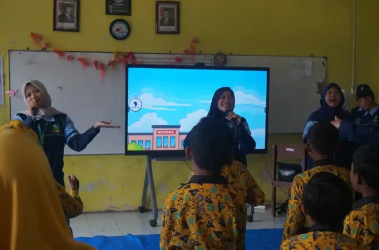 Dua mahasiswa KKN UIN Walisongo memberikan edukasi anti bullying secara interaktif menggunakan layar digital kepada siswa SD Babat 1 Demak yang berseragam batik kuning di dalam kelas.
