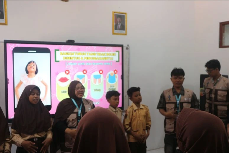 Mahasiswa KKN UIN Walisongo memandu siswa pramuka SDN Podosoko 1 Magelang di depan layar interaktif yang menampilkan batas larangan sentuhan tubuh, sebagai bagian dari edukasi seksual anak dan perlindungan anak usia dini.
