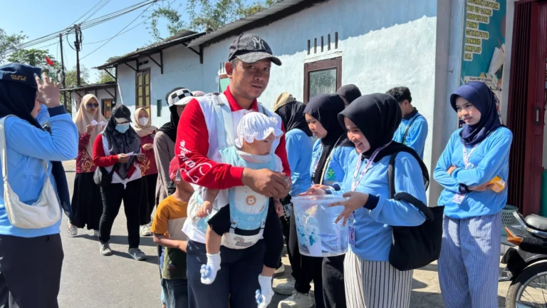 Mahasiswa KKN UIN Walisongo berinteraksi dengan warga yang menggendong anak saat mengumpulkan kupon undian acara jalan sehat Bansari Temanggung.
