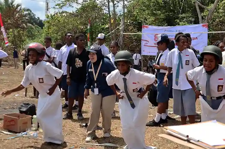 Anak-anak perbatasan di Distrik Senggi mengikuti lomba balap karung unik memakai helm, didampingi mahasiswa Undip Papua dalam perayaan HUT RI.