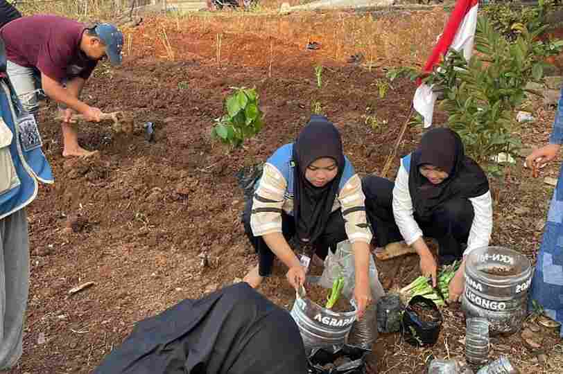 Warga dan mahasiswa bergotong royong menanam bibit tanaman herbal di sebuah lahan kosong sebagai wujud nyata pemanfaatan lahan terbengkalai menjadi kebun produktif.