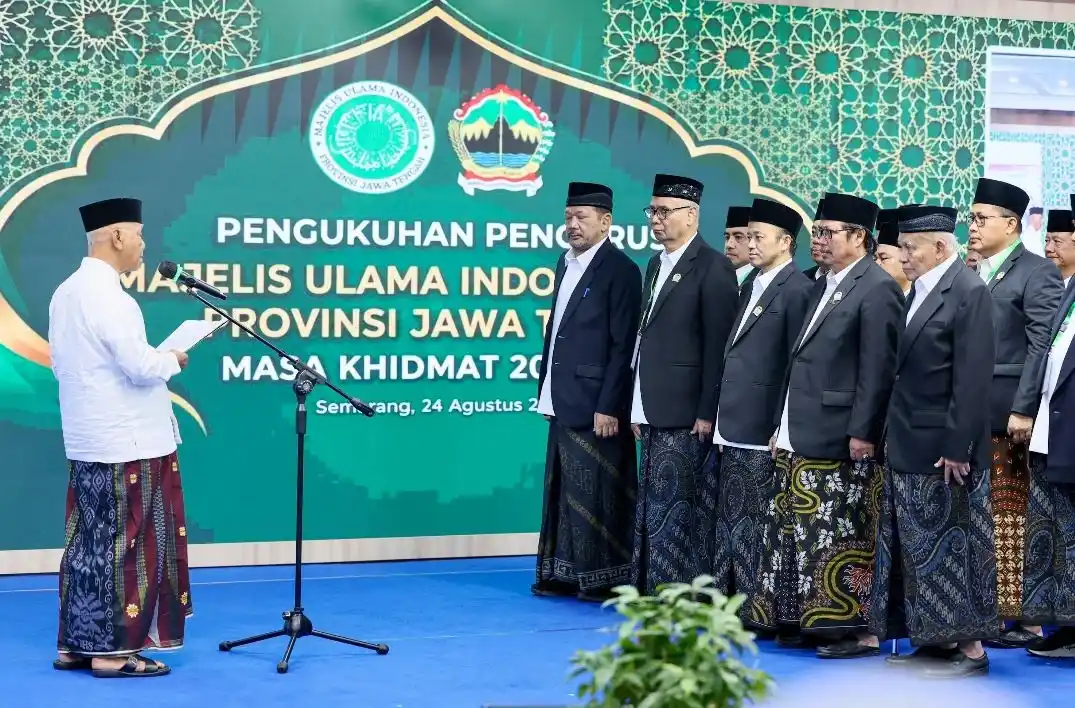 Suasana khidmat prosesi pembacaan naskah pengukuhan Pengurus MUI Jateng 2026-2031 oleh Ketua Umum MUI Pusat di Gradhika Bhakti Praja, Semarang. Tampak jajaran pengurus baru dari unsur ulama dan akademisi berdiri berbaris mengenakan jas hitam, peci, dan kain sarung.