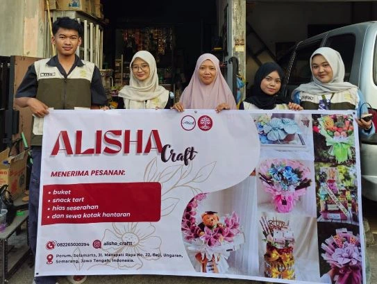 Mahasiswa KKN UIN Walisongo mendampingi pemilik Alisha Craft membentangkan spanduk baru hasil program rebranding UMKM di Perum Selamarta, Ungaran.