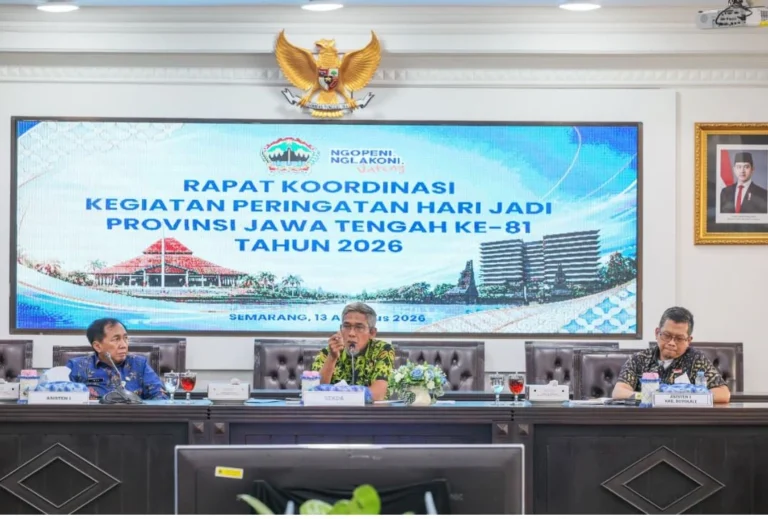 Tiga pejabat pria duduk di meja rapat besar dengan pejabat tengah, Sekda Jateng Sumarno, berbicara melalui mikrofon. Di latar belakang terdapat layar LED besar menampilkan teks: "RAPAT KOORDINASI KEGIATAN PERINGATAN HARI JADI PROVINSI JAWA TENGAH KE-81 TAHUN 2026" dan logo Jateng. Di atas layar terpasang lambang Garuda Pancasila emas. Di kanan terdapat foto Presiden Joko Widodo.
