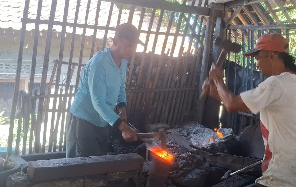 Dua perajin pandai besi di Desa Gondowangi, Magelang, sedang bekerja menempa besi panas di bengkel tradisional. Mereka adalah pelaku usaha yang kini terlibat dalam transformasi digital UMKM Gondowangi Magelang.
