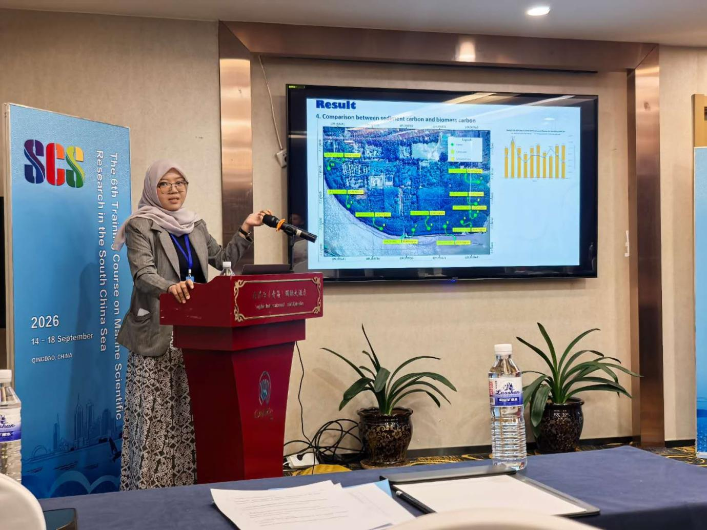Delegasi Peneliti Unsoed yang mengenakan jas abu-abu dan hijab sedang mempresentasikan hasil riset di podium pada acara 6th Training Course on Marine Scientific Research in the South China Sea di Qingdao, China.