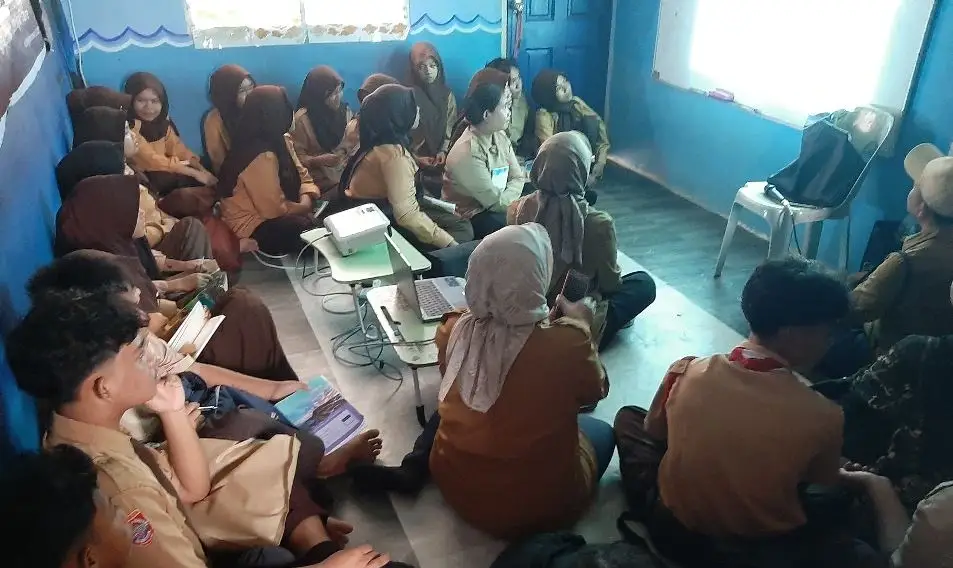 Suasana puluhan siswa berseragam pramuka yang merupakan anak pekerja migran sedang duduk lesehan menatap layar proyektor di ruang kelas CLC Ladong Simunjan.