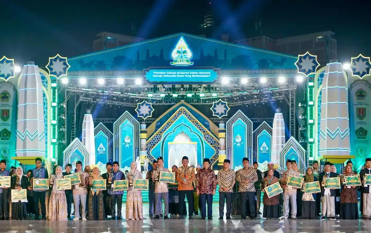 Puluhan pemenang berfoto bersama jajaran pejabat dan dewan hakim sambil memegang piagam penghargaan pada malam pengumuman Daftar Lengkap Juara MTQ Nasional 2026 di panggung utama Simpang Lima, Semarang.
