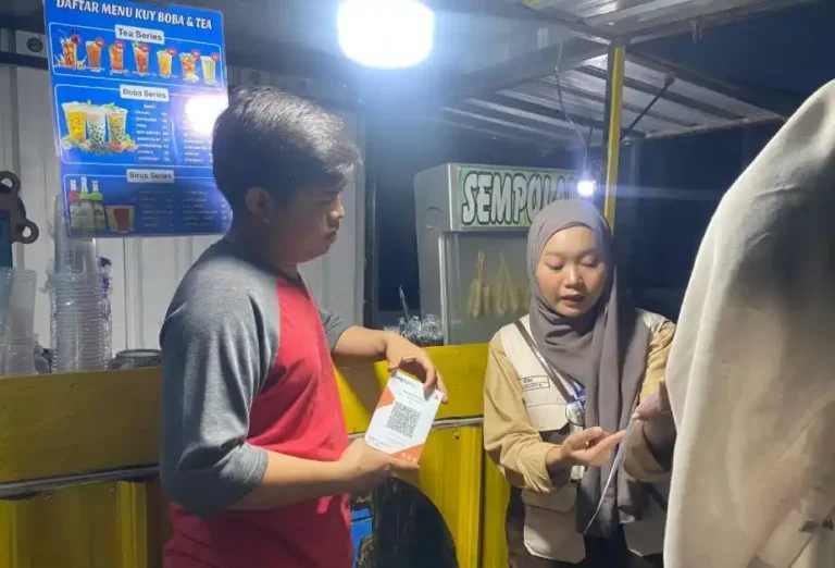 Mahasiswa KKN menjelaskan panduan transaksi digital sambil memegang cetakan QRIS untuk UMKM kepada pedagang kedai Kuy Boba & Tea di Desa Tangkis, Demak.