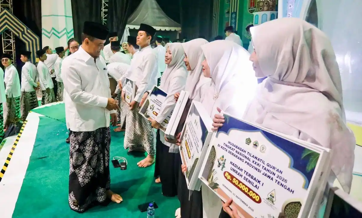 Gubernur Jawa Tengah menyerahkan hadiah juara MTQ nasional berupa simbolis tiket umrah dan uang pembinaan kepada para kafilah berprestasi di atas panggung.