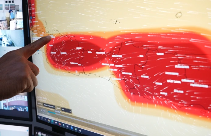 Petugas menunjuk peta prakiraan cuaca di layar monitor BMKG yang menunjukkan indikator warna merah pekat saat cuaca panas Jawa Tengah.