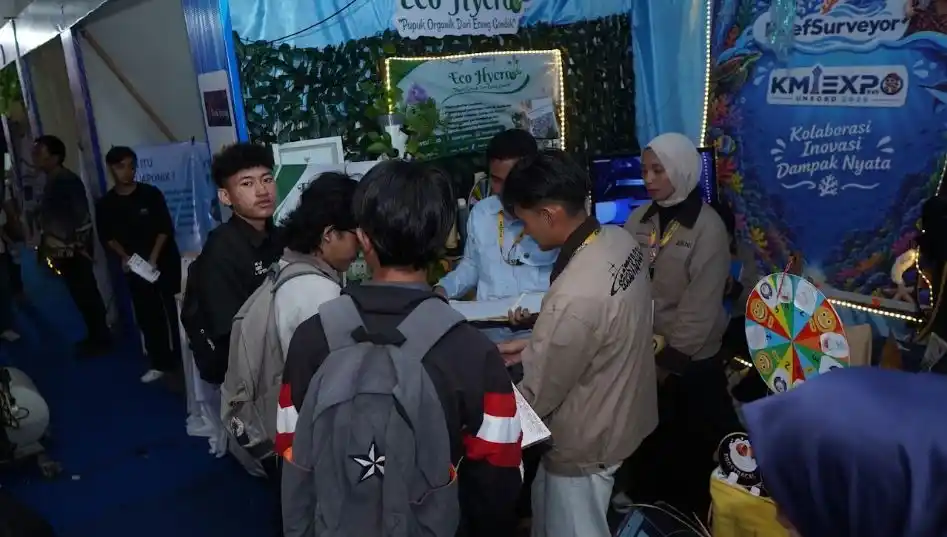 Sejumlah mahasiswa sedang berdiskusi di depan stan pameran inovasi pupuk organik dengan latar belakang spanduk KMI Expo Unsoed 2026 bertuliskan Kolaborasi Inovasi Dampak Nyata.