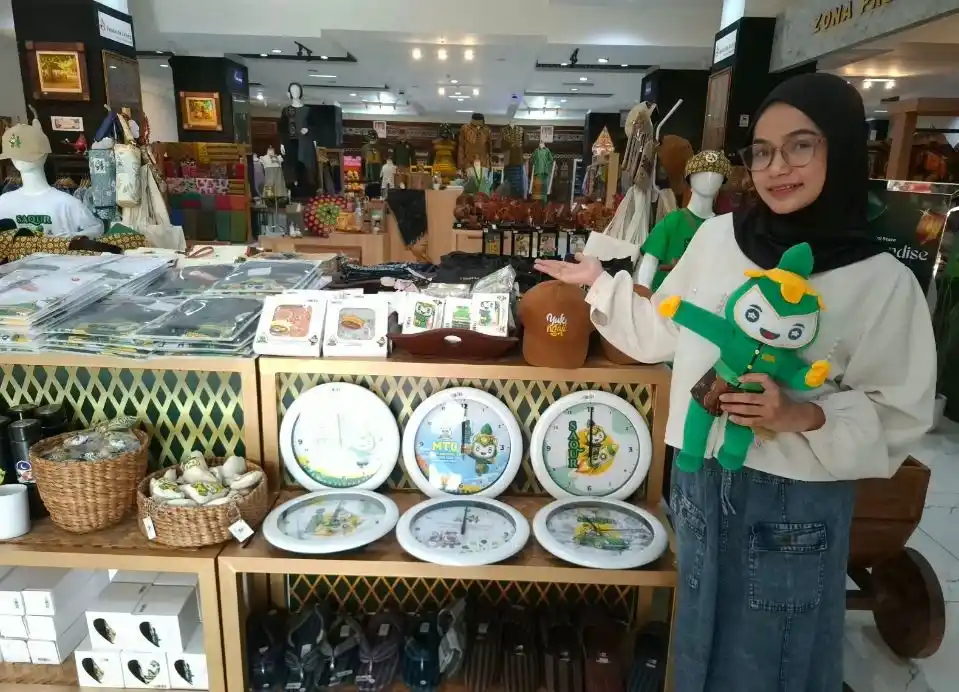 Pengunjung menunjukkan boneka maskot Saqur dan ragam suvenir resmi MTQ Nasional 2026 karya IKM lokal di Dekranasda Store Jawa Tengah.