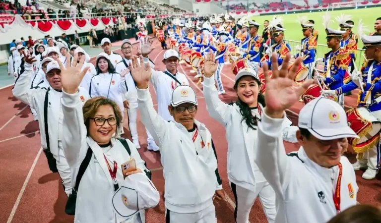 Barisan kontingen berjaket putih melambaikan tangan diiringi marching band dalam kemeriahan pembukaan Porprov Jateng 2026 di Stadion Jatidiri Semarang